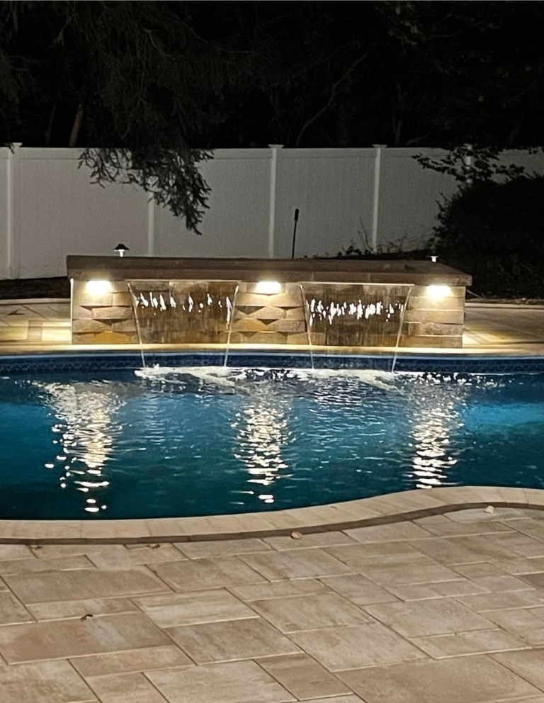 Illuminated pool waterfall at night